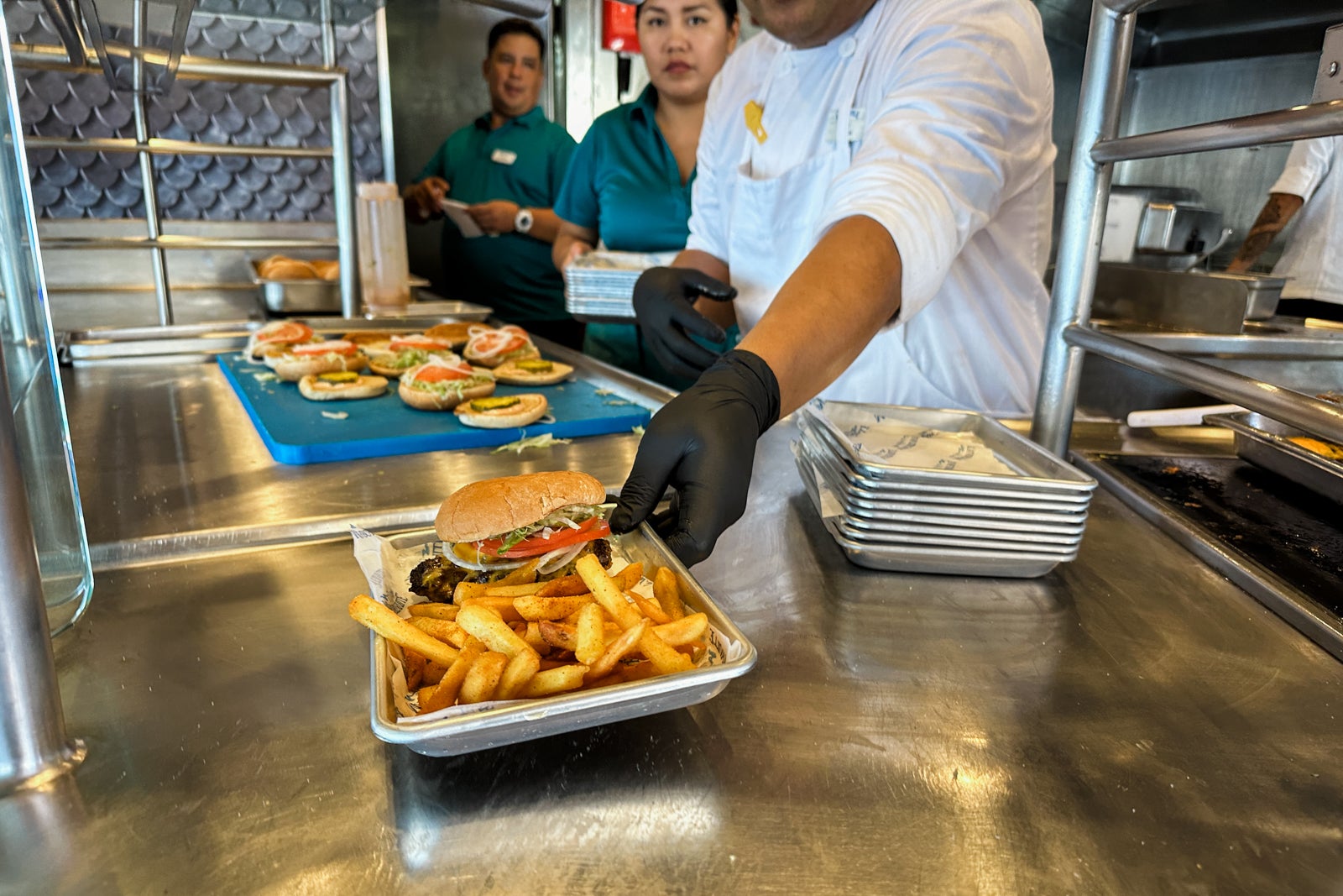 A crew member handing the camera a cheeseburger on a cruise ship