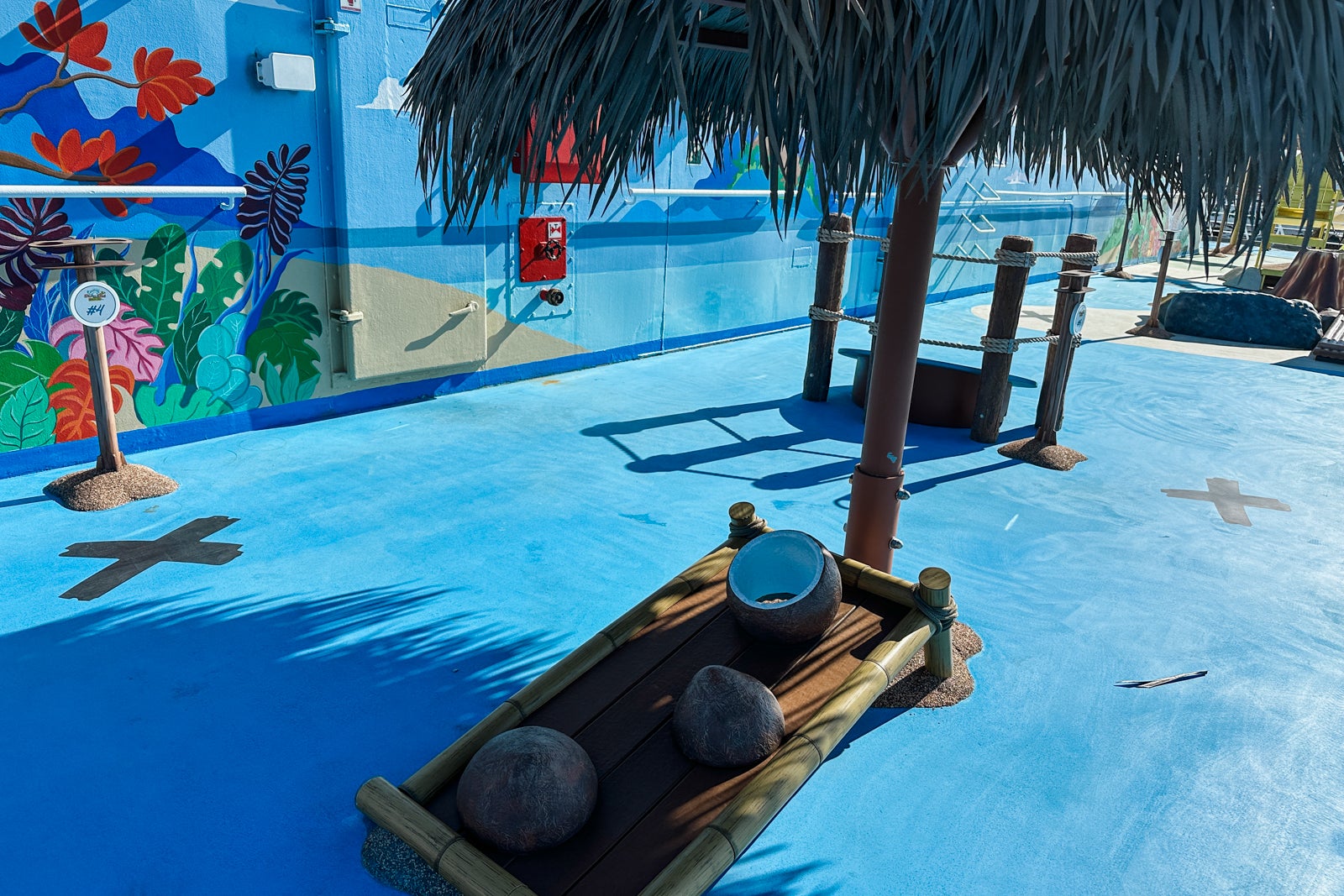 Part of a cornhole course with obstacles on the top deck of a cruise ship