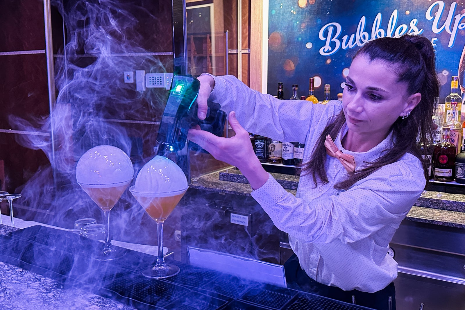 A bartender makes a pair of cocktails with smoke bubbles on top