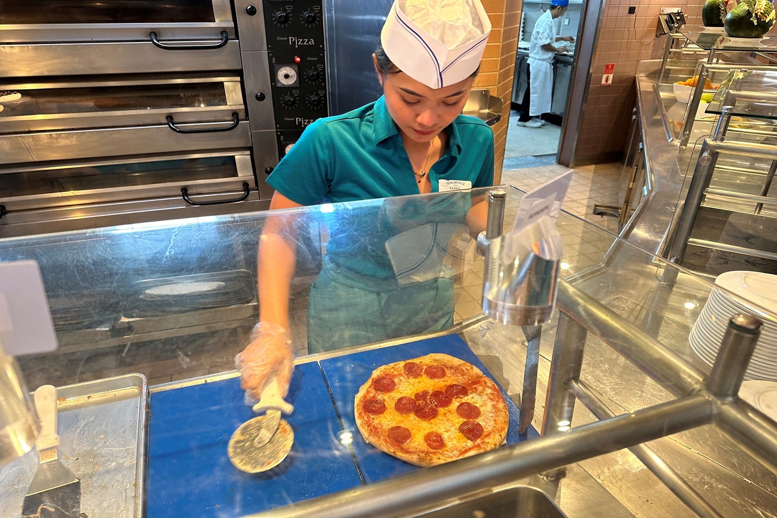 A crew member cutting pizza on a cruise ship