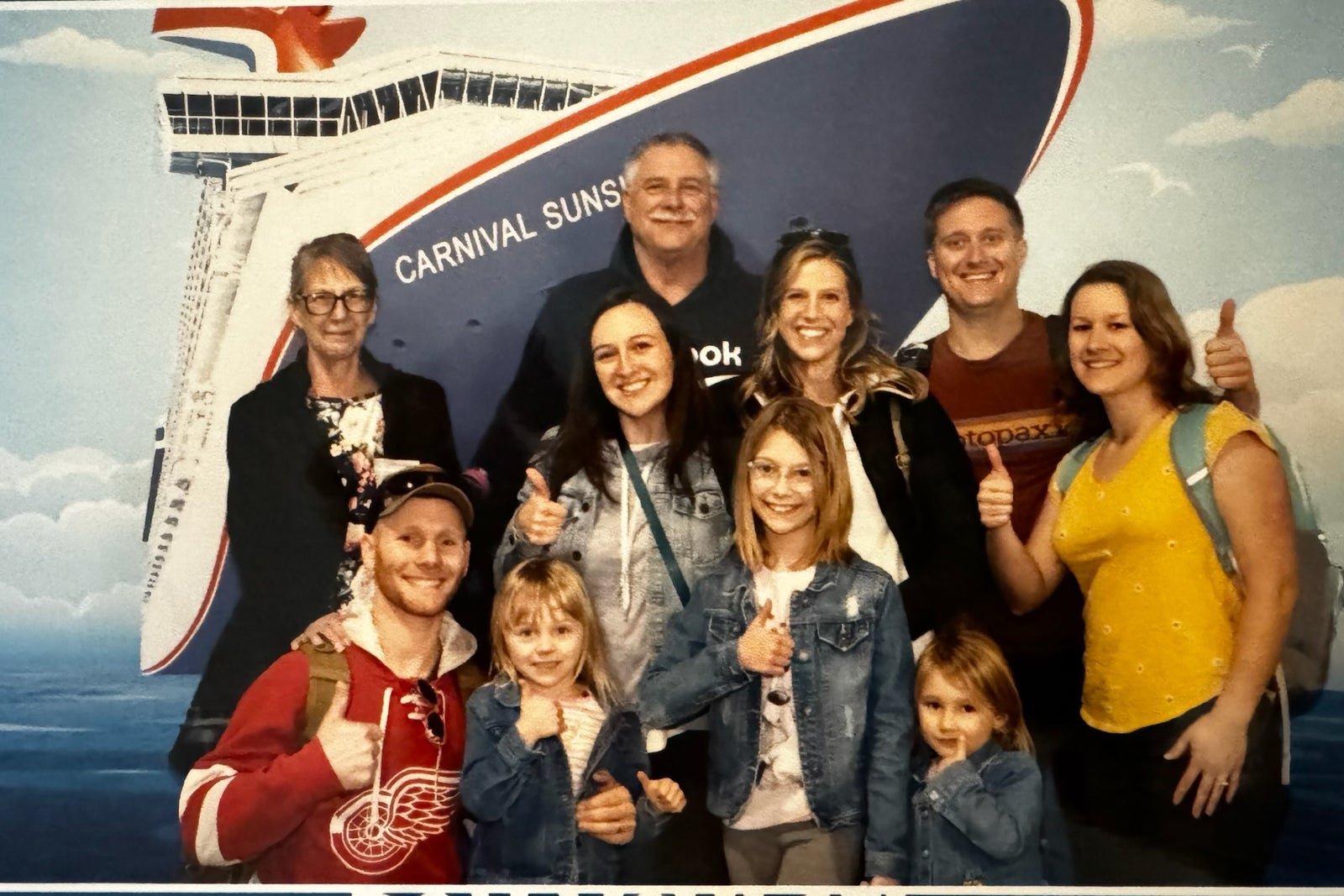 multigenerational family group posing in front of Carnival cruise sign