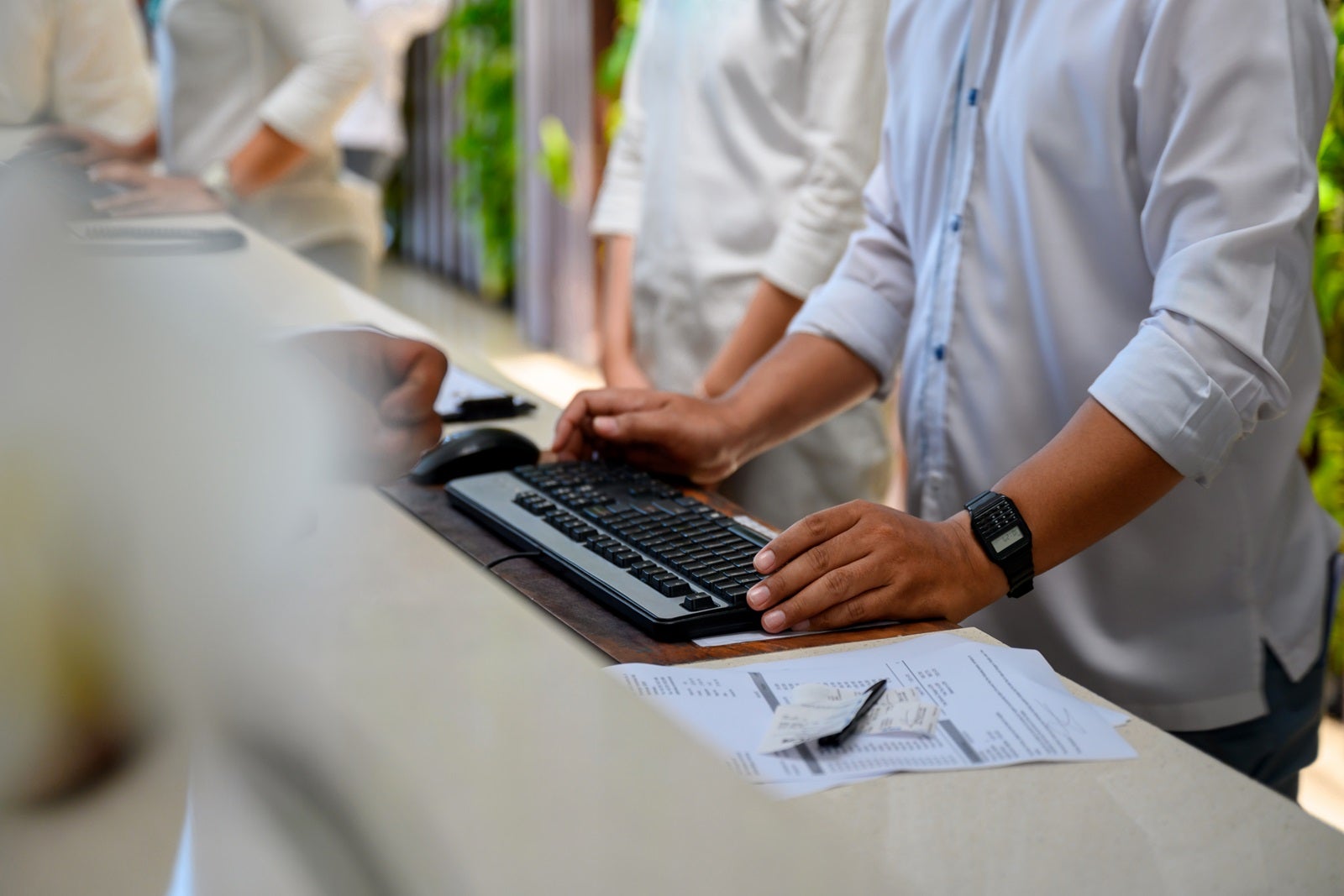 The arms and hands of someone checking in a traveler at a desk