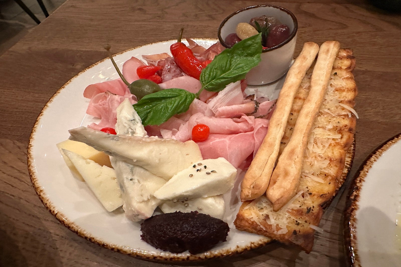 A plate of meat, cheese and breadsticks