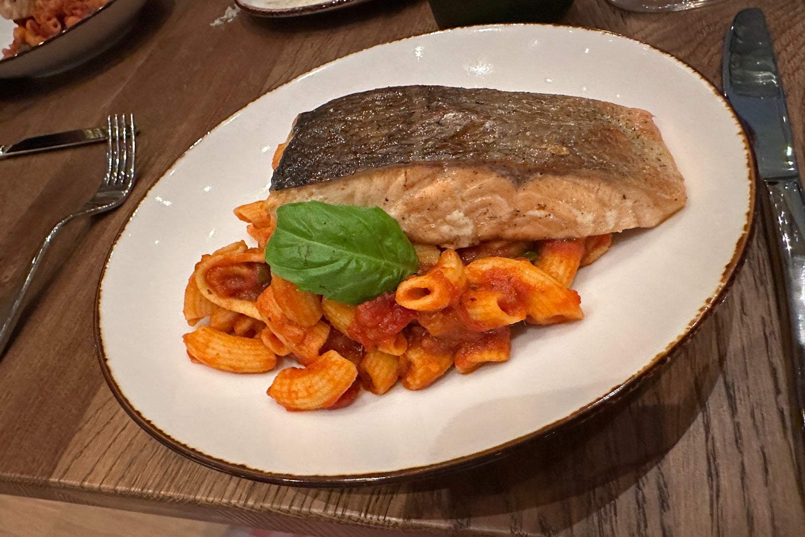 A plate of salmon with pasta and sauce