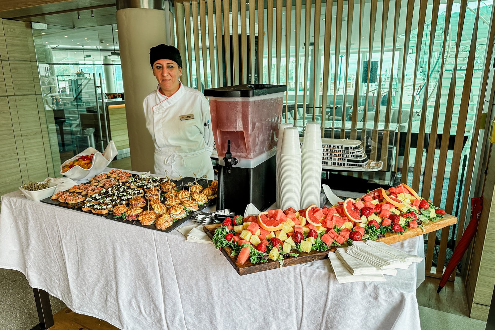 A crew member stands behind a spread of pre-dinner appetizers on a cruise ship