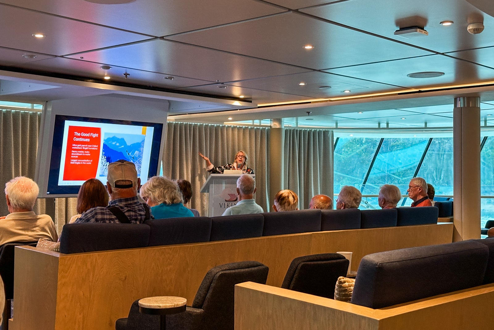 A cruise ship lecturer gives a talk in a lounge