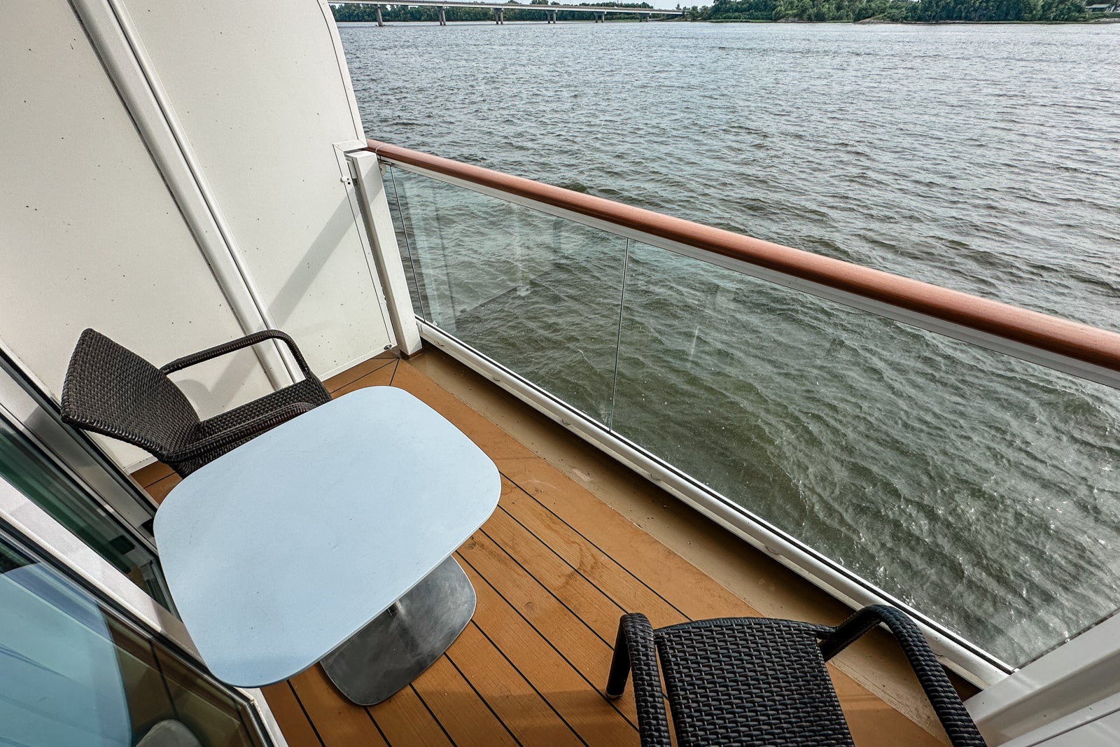 A cruise ship balcony with two chairs and a drinks table