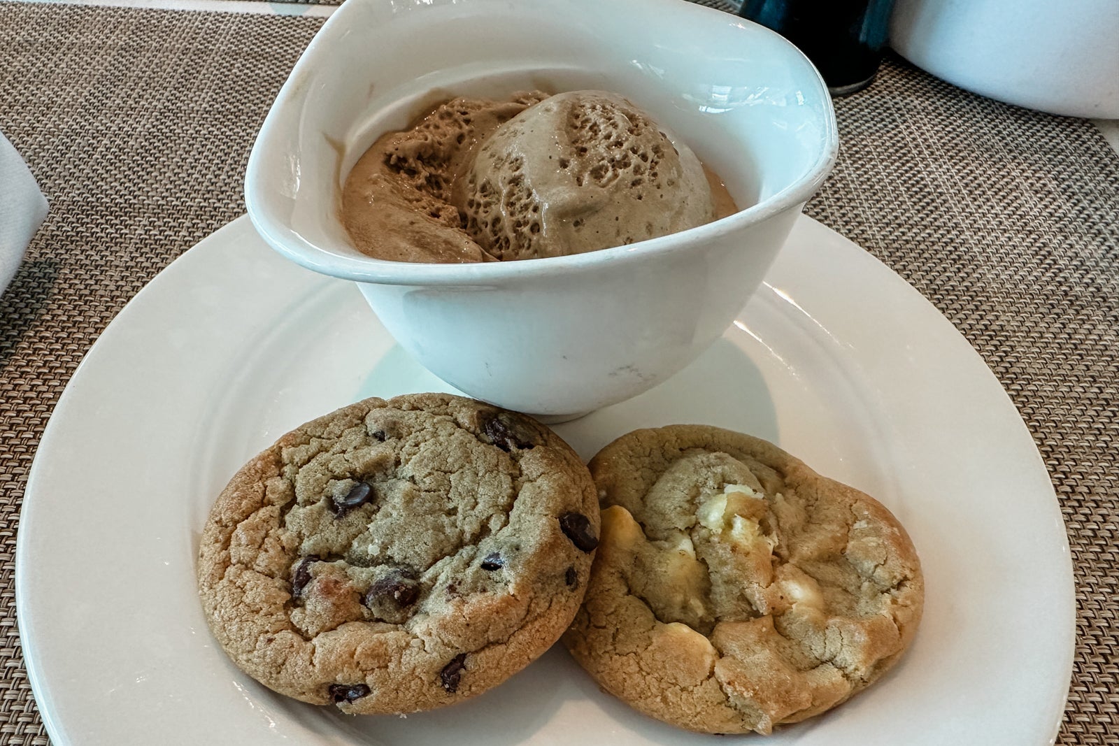 A plate with two cookies and a bowl of ice cream