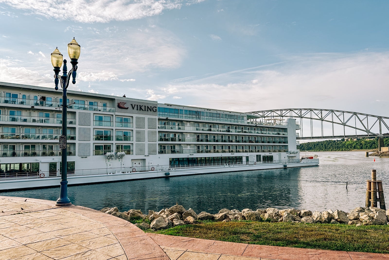 A riverboat docked next to a light pole in front of a bridge