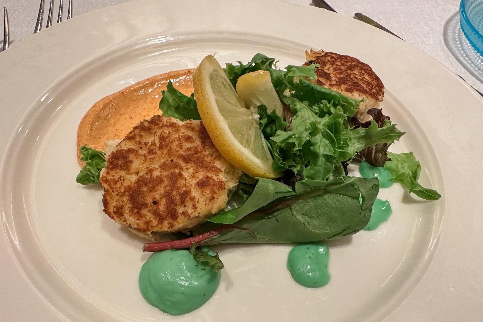 A white plate with crab beignets and vegetables