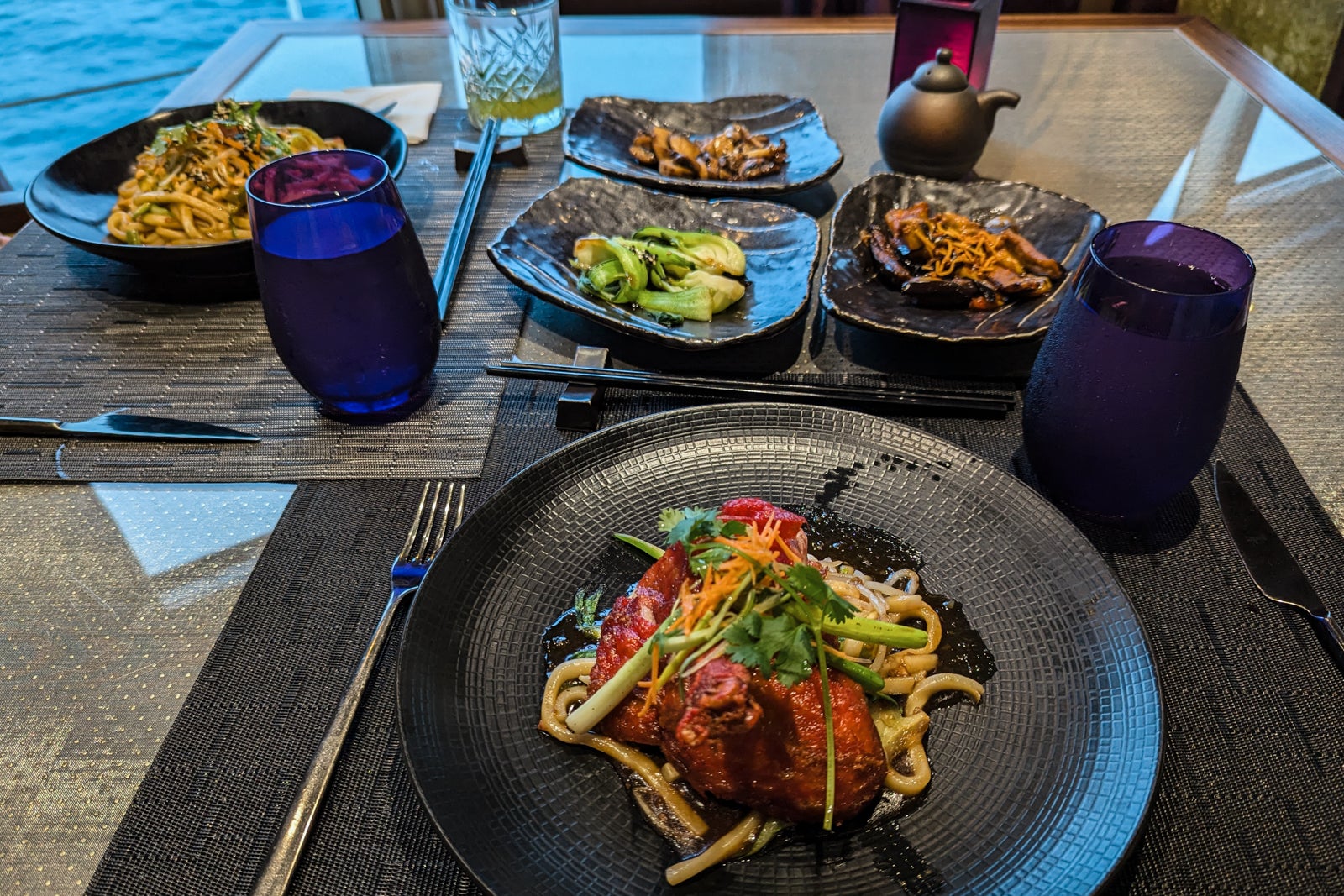 Table full of black plates with Asian food