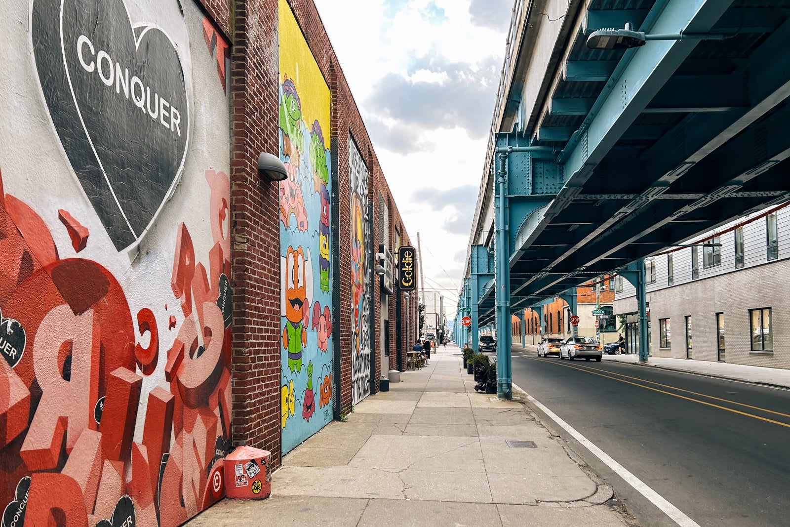 city wall with murals underneath an elevated train track