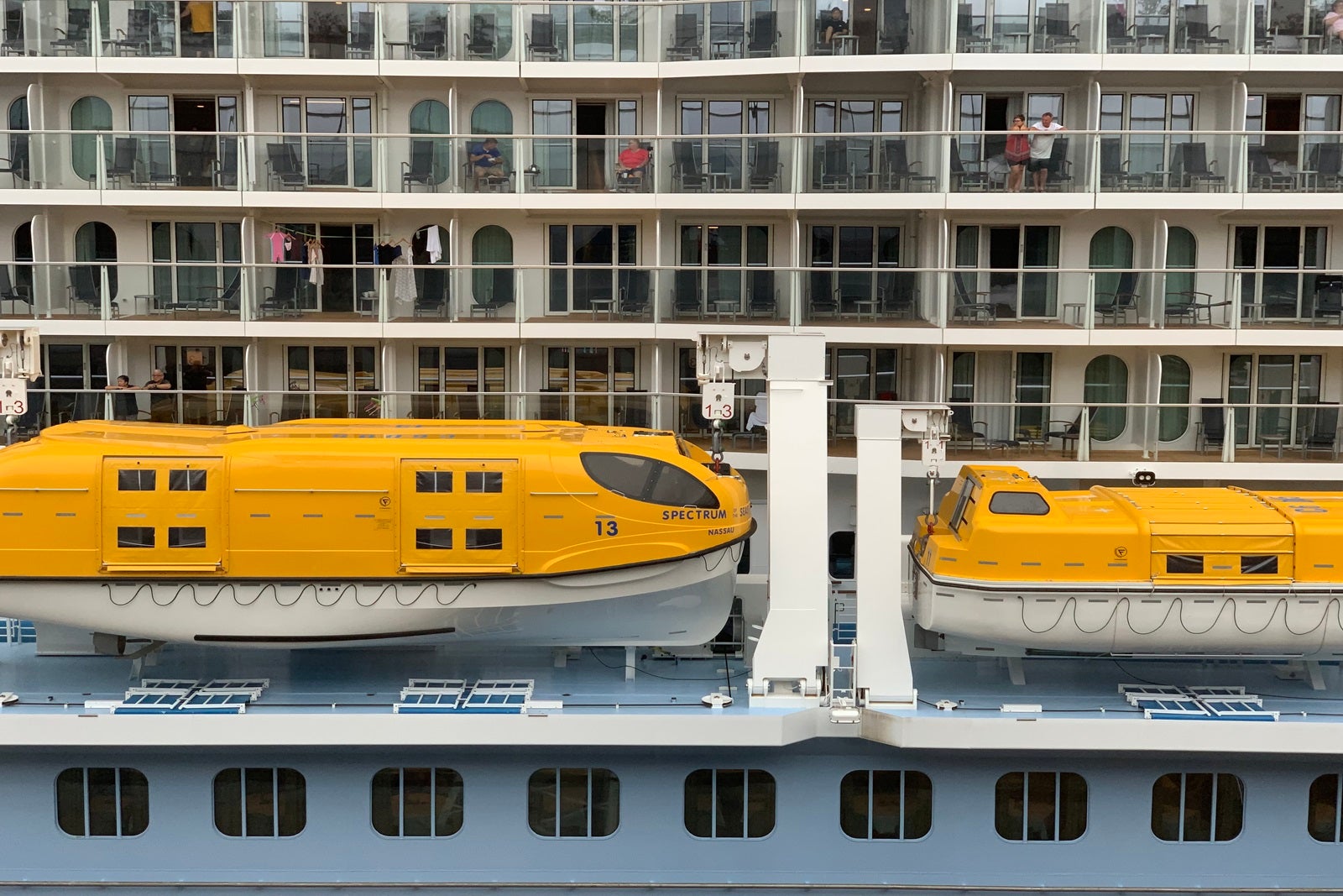 Yellow and white lifeboats hanging off the side of a cruise ship