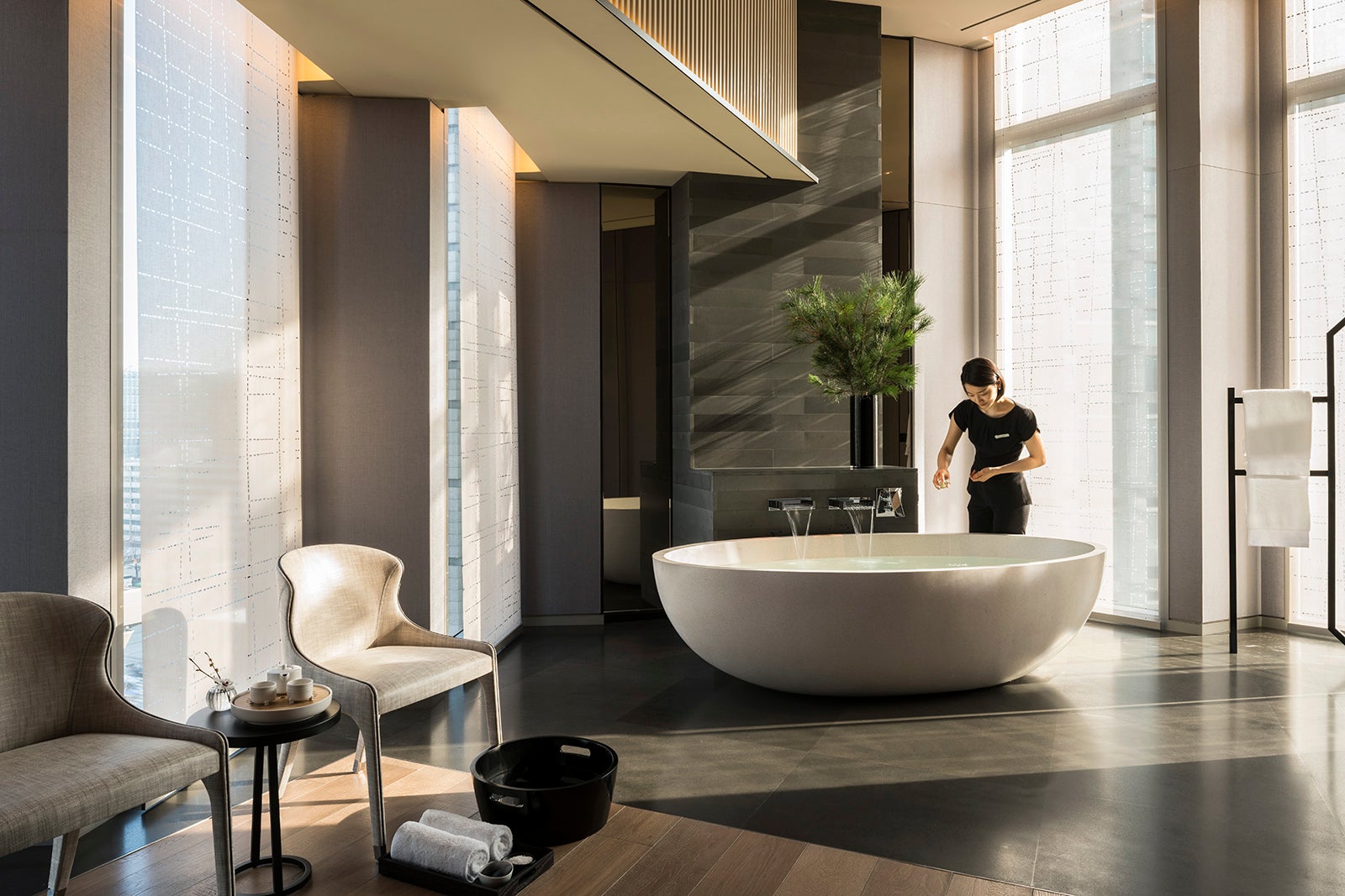 woman standing over bathtub in large treatment room at hotel spa