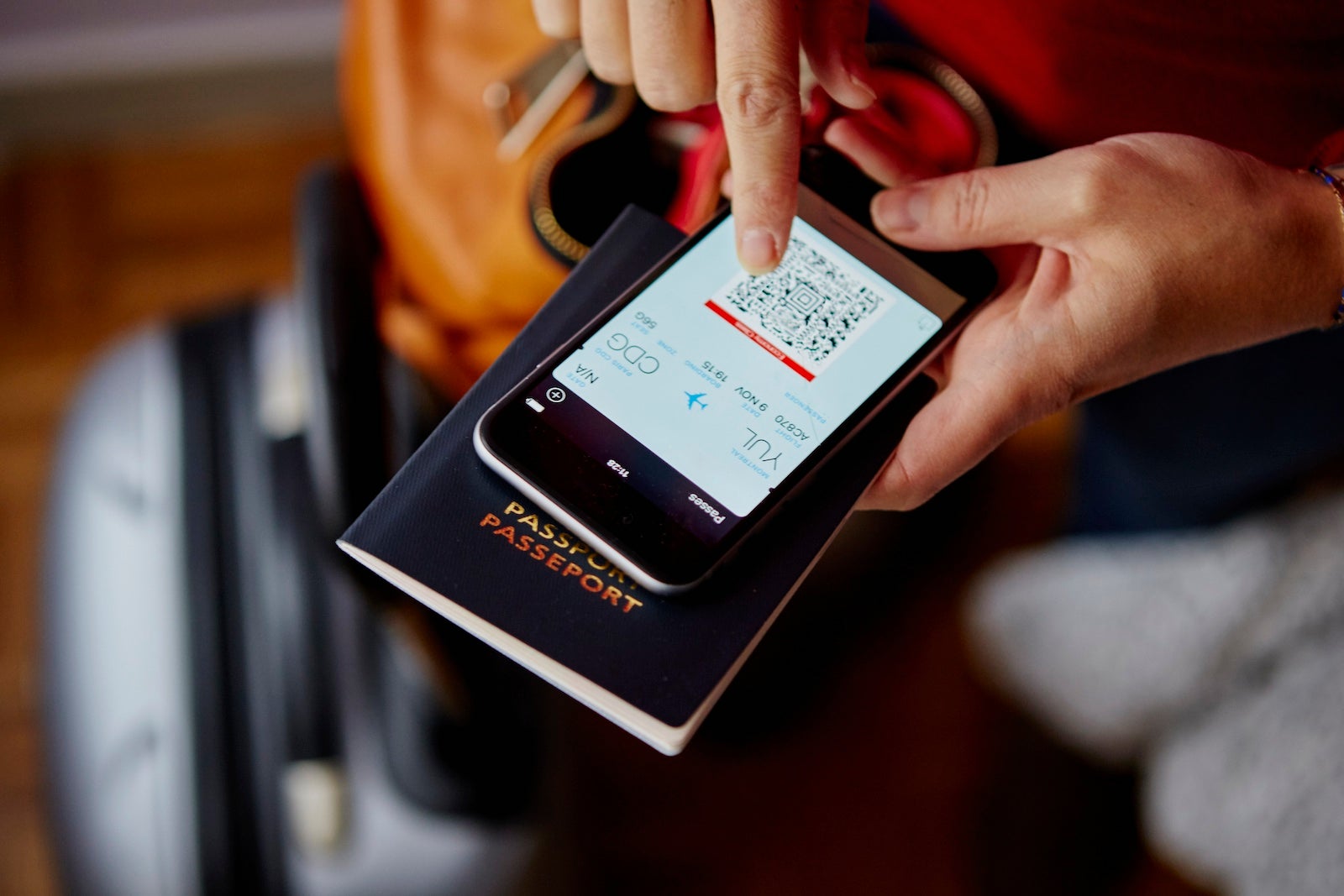 Woman holding passport and smartphone, smartphone showing QR code, overhead view