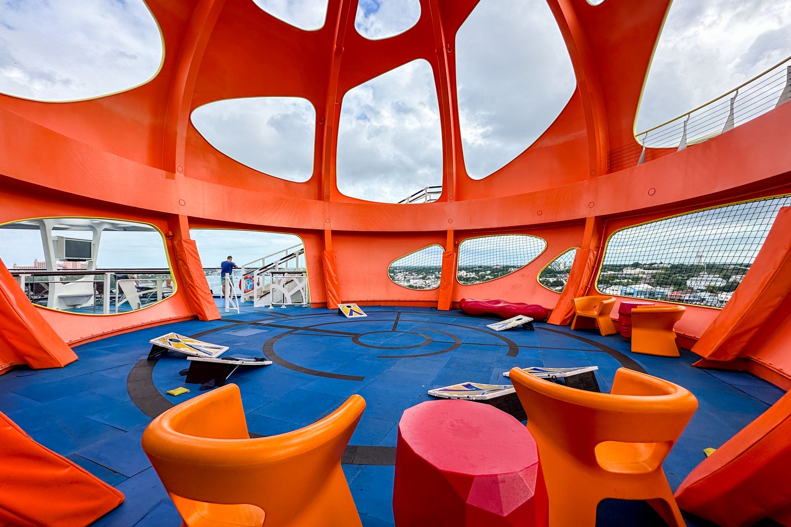 An outdoor activity area under an orange metal sphere with beanbag games