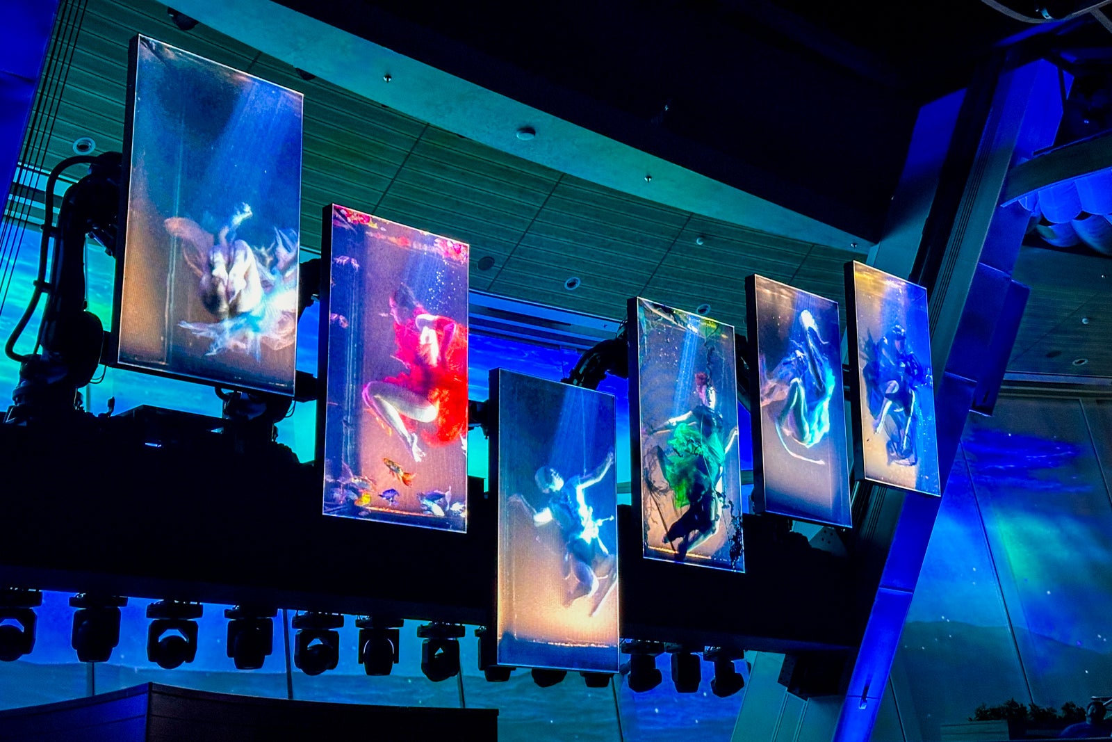 A series of "dancing" TVs suspended in front of a giant LED wall in a cruise ship lounge