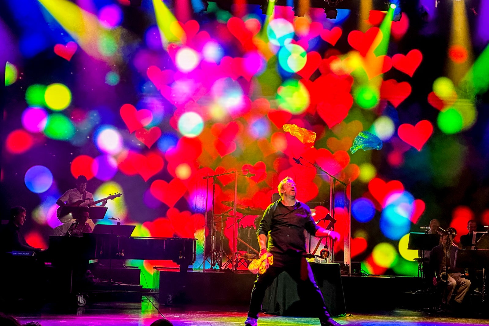 A juggler performing in the theater on a cruise ship with a brightly colored screen behind him