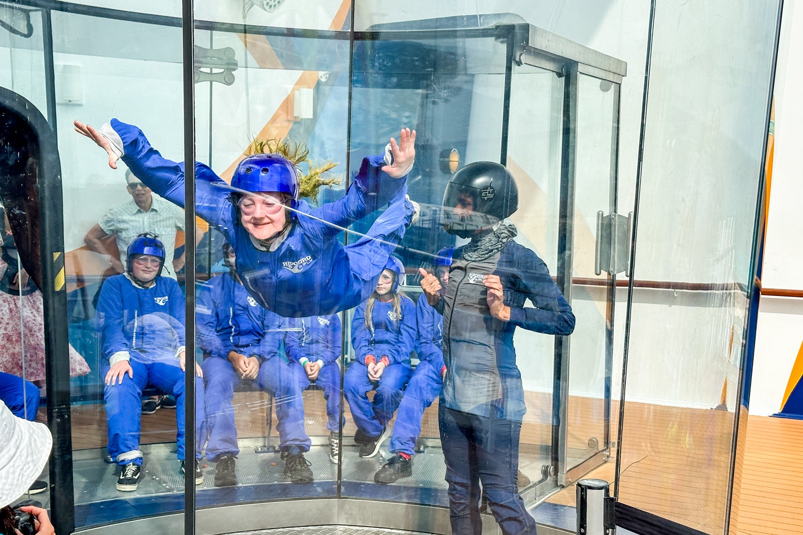 A passenger on a cruise ship tries a skydiving simulator in a giant see-through wind tube