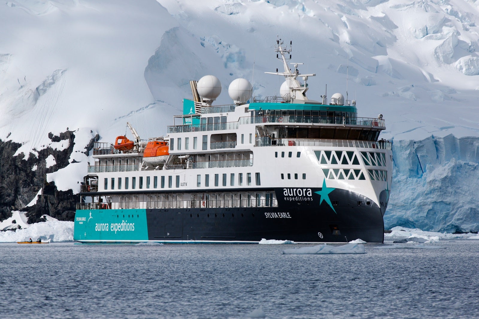 An expedition cruise ship anchored in front of a glacier in Antarctica