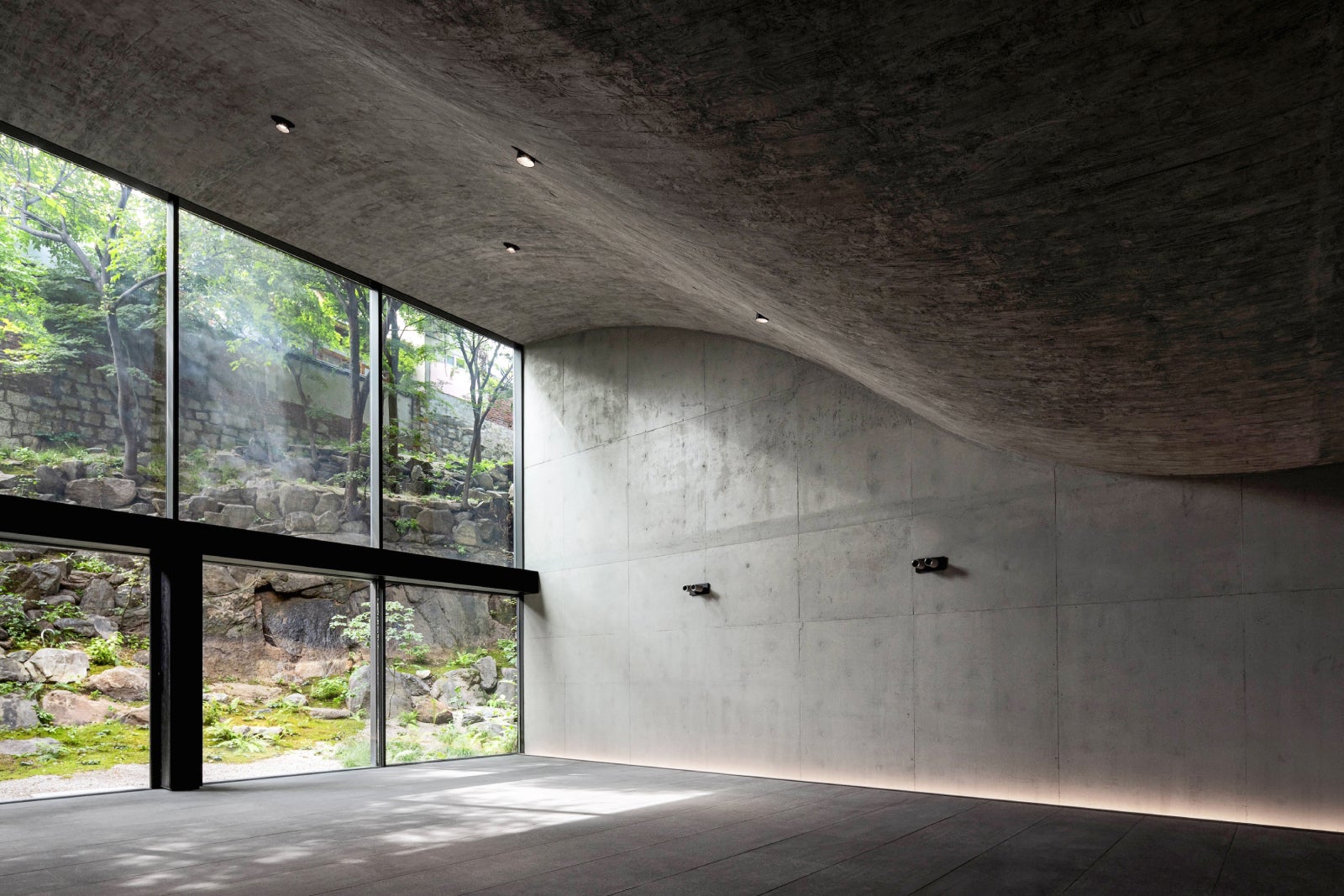 Empty concrete room with waved ceiling and floor to ceiling glass wall