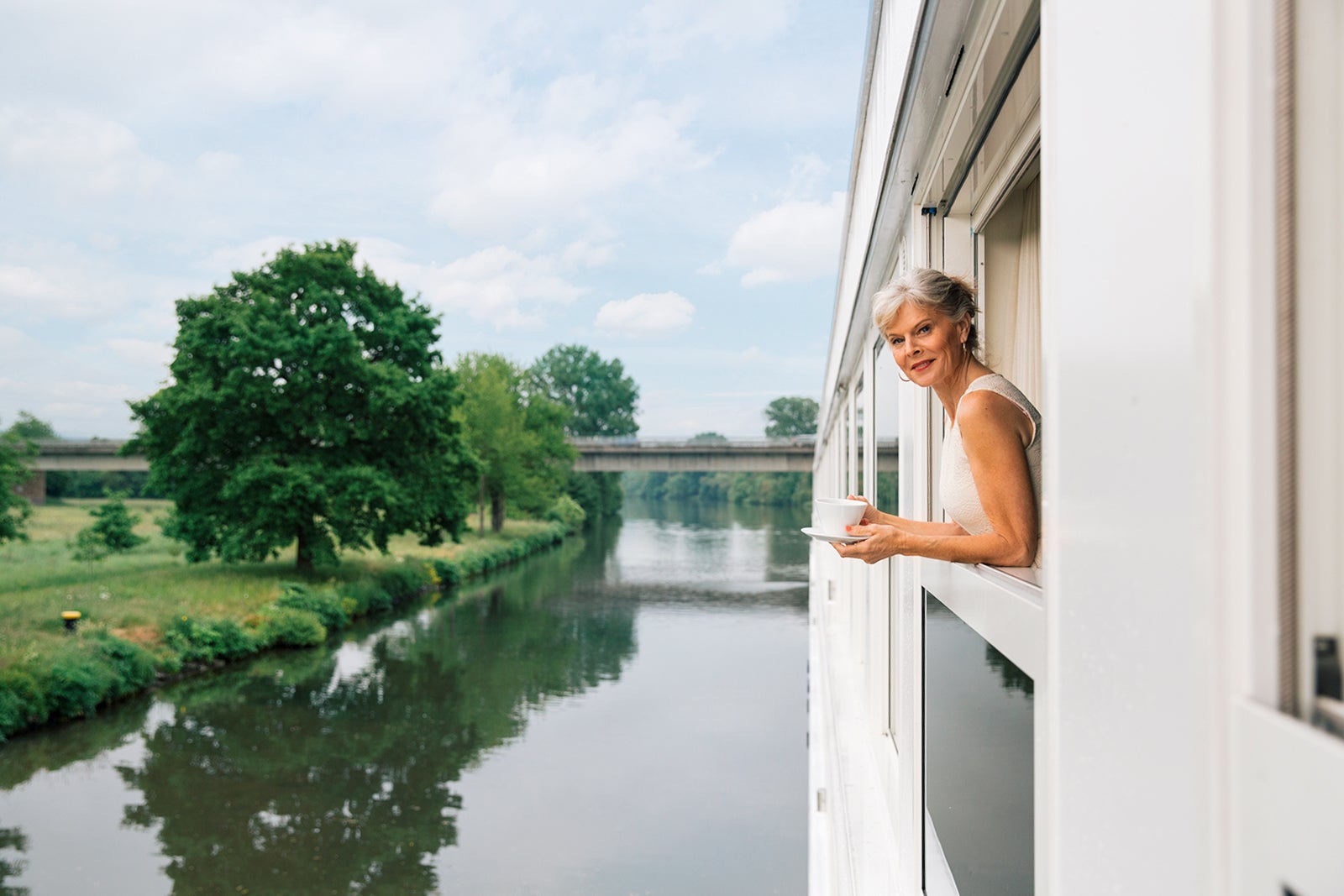 A woman looks out off the balcony of her cabin on a river cruise ship