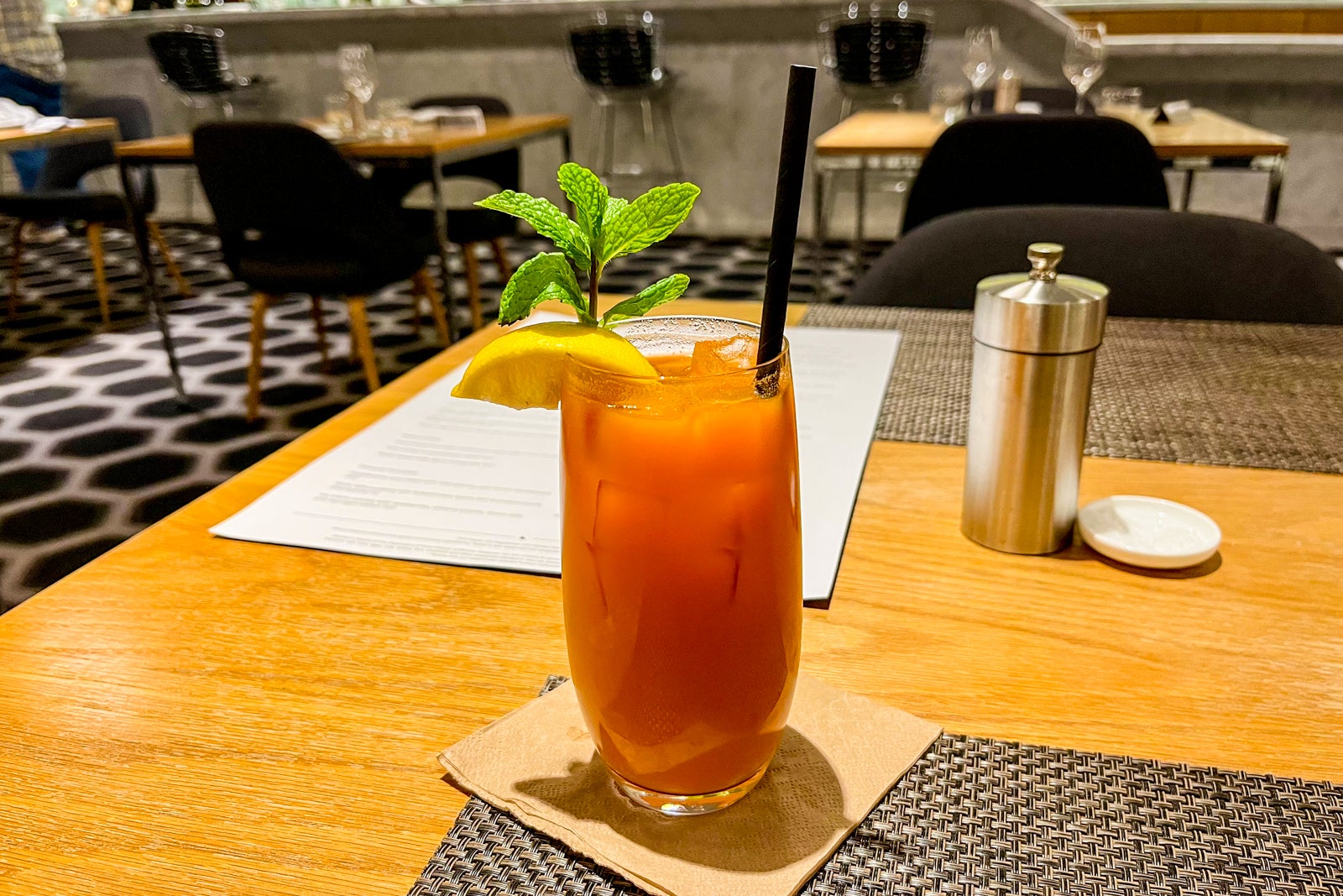 a glass filled with a deep orange drink sits on a wood table