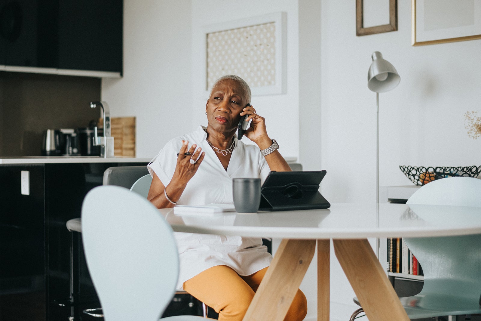 Elderly Black woman sitting at a table talking on the phone.