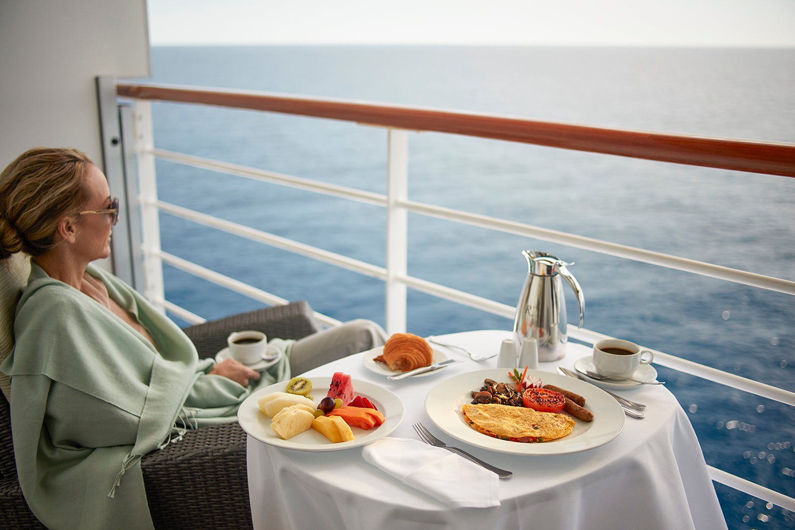 Woman enjoys room service breakfast on cruise ship balcony