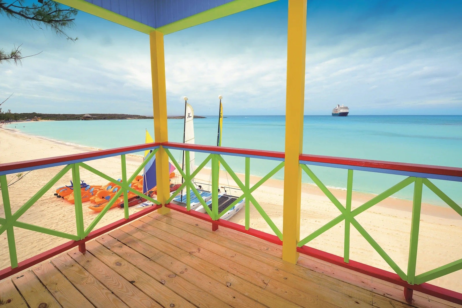 A view of the sand and water from a beach villa with colorful railings on Half Moon Cay