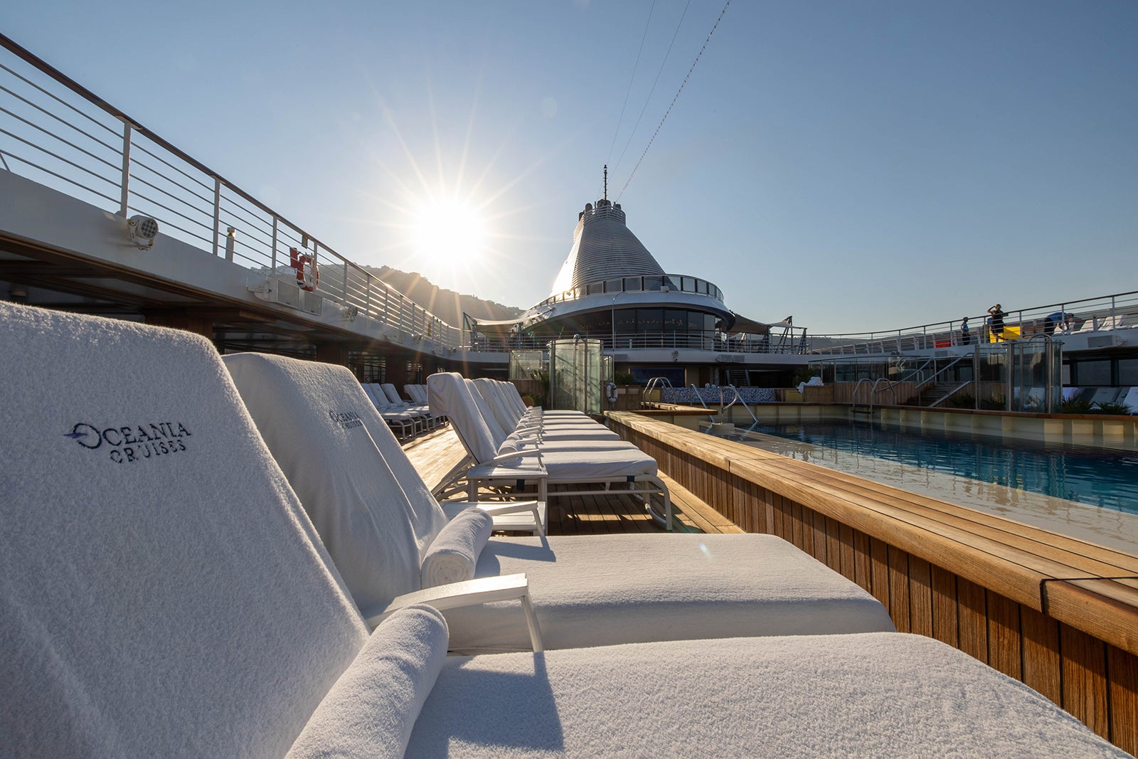 Cruise ship pool deck with white covered lounge chairs