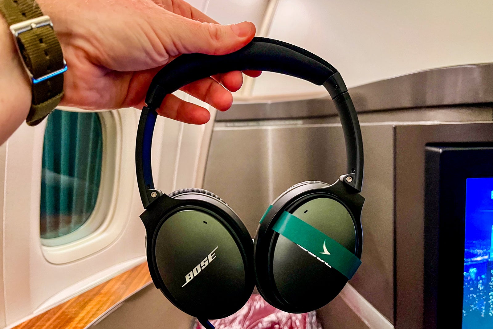 a hand holds a pair of headphones featuring a Bose logo