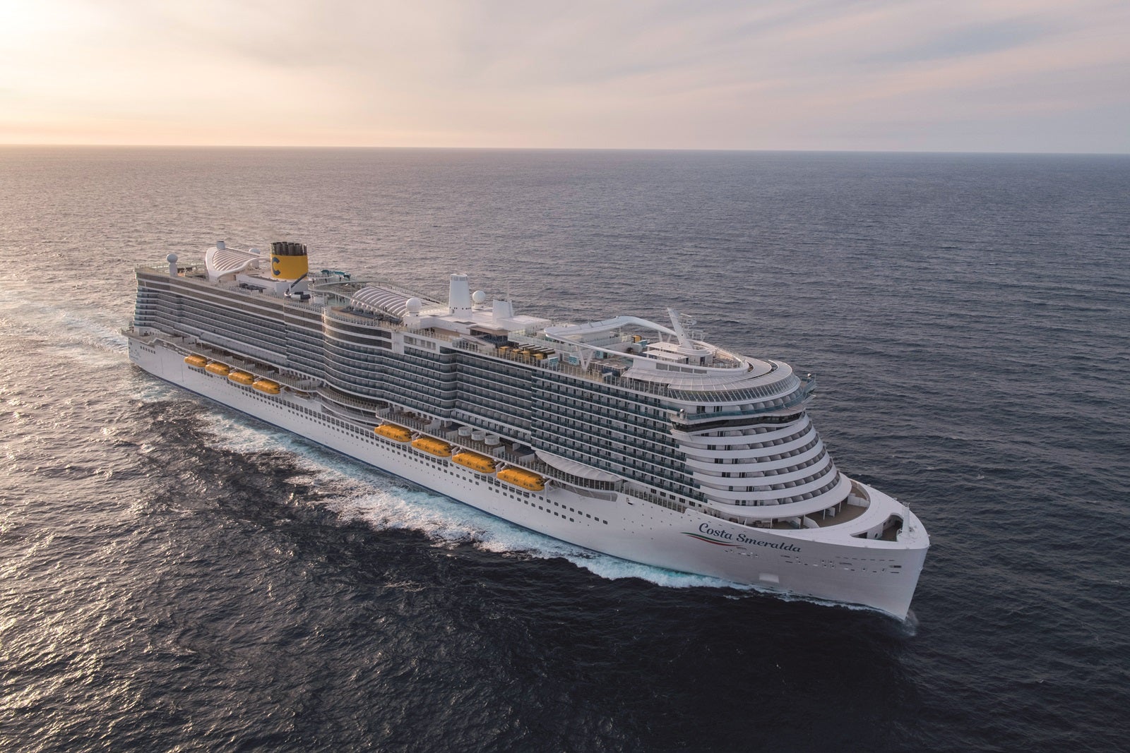 A white cruise ship at sea with yellow lifeboats