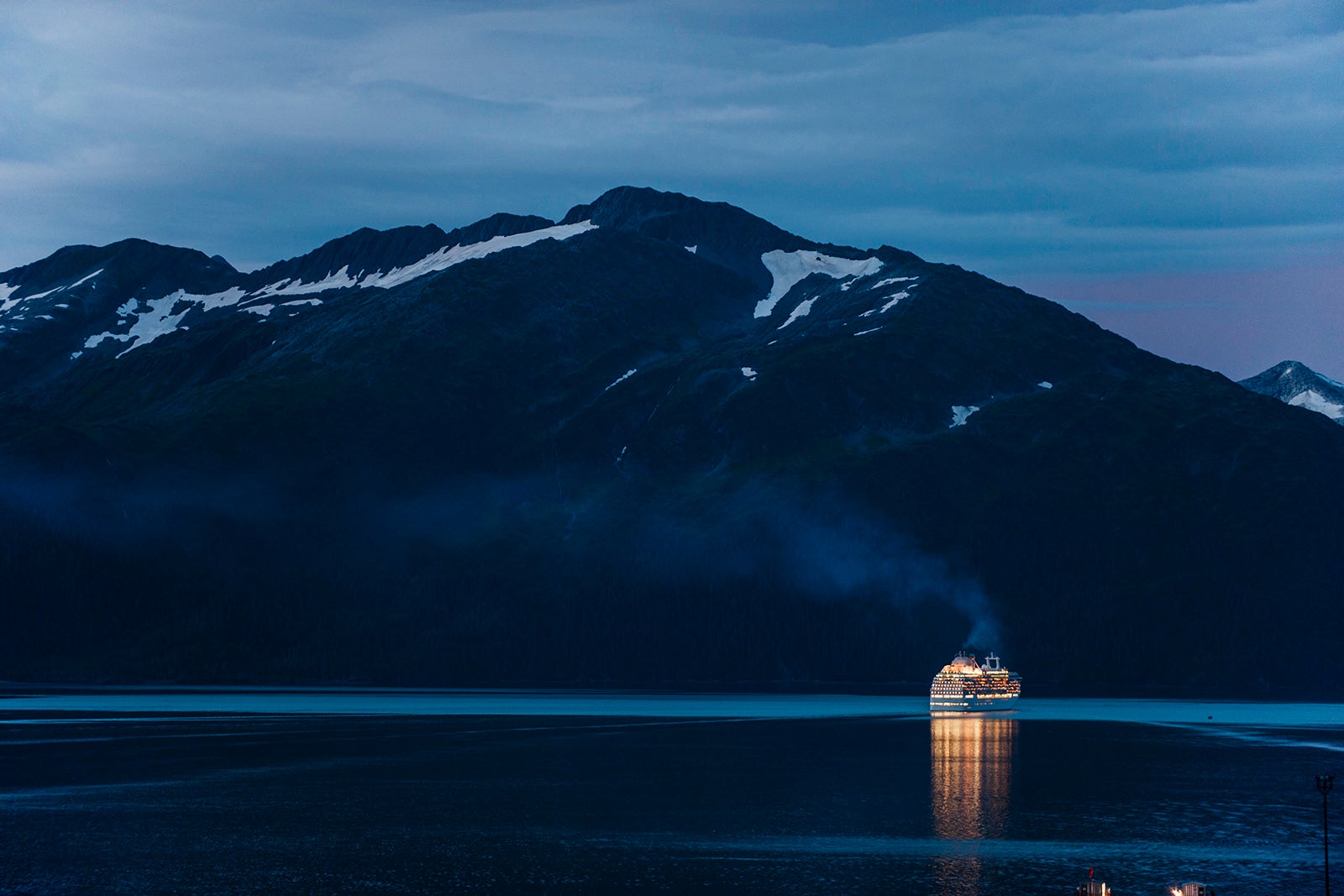 A cruise ship departs Whittier, AK into Prince William Sound in the late evening.